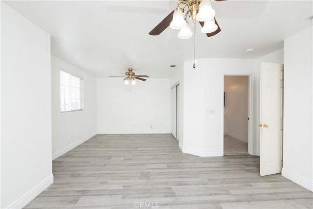 empty room featuring baseboards, a ceiling fan, and light wood finished floors