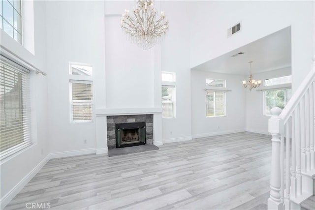 unfurnished living room featuring stairs, an inviting chandelier, visible vents, and light wood-style floors