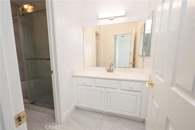 full bath with vanity, baseboards, and a shower stall