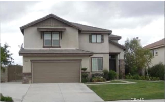 view of front of property featuring a garage, concrete driveway, a front yard, and stucco siding