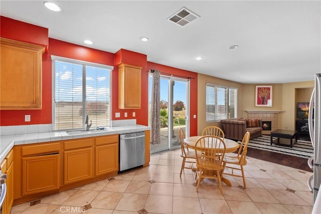 8309 Clover Creek Rd, Riverside, CA 92508 - kitchen featuring stainless steel dishwasher, a sink, a tile fireplace, recessed lighting, and tile countertops