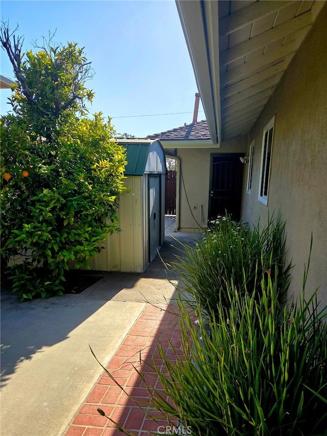 view of property exterior with a patio, an outbuilding, a shed, and stucco siding