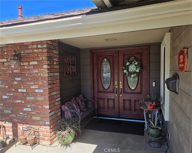 entrance to property with a porch and brick siding