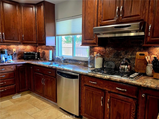 kitchen featuring a sink, stainless steel appliances, backsplash, a toaster, and under cabinet range hood