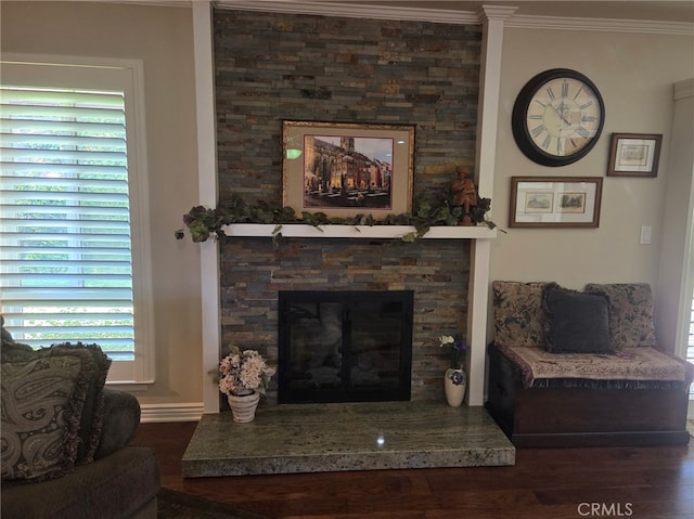 living room with crown molding, plenty of natural light, a fireplace, and wood finished floors
