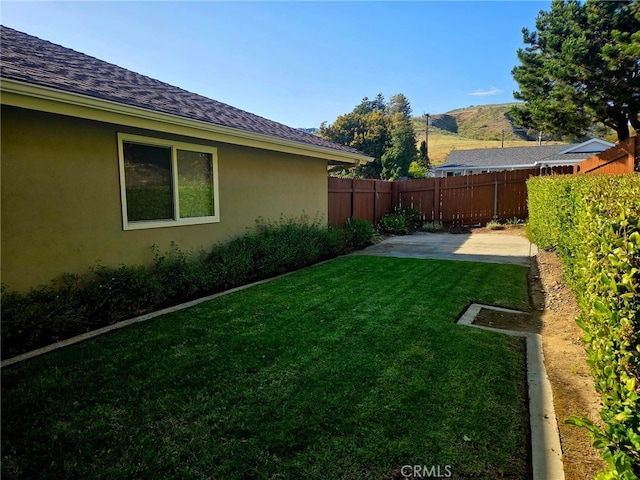 view of yard featuring a patio, a fenced backyard, and a mountain view