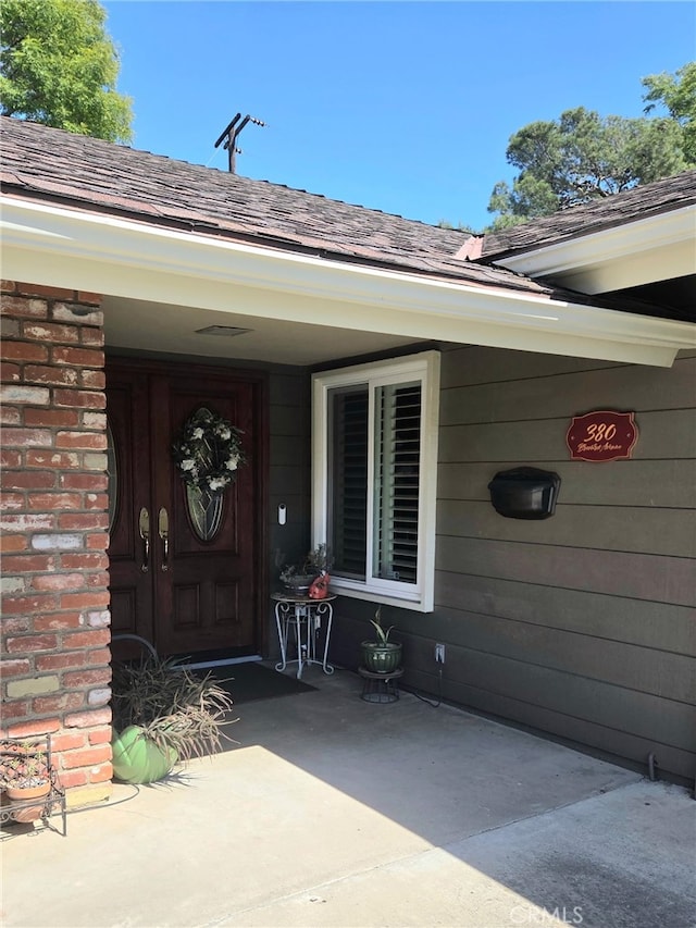 view of exterior entry with a shingled roof