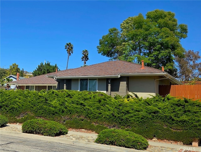 ranch-style house featuring fence and stucco siding