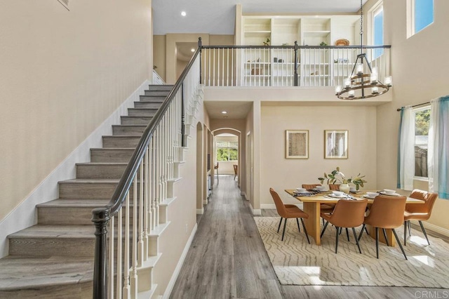 interior space featuring arched walkways, a towering ceiling, wood finished floors, and stairway