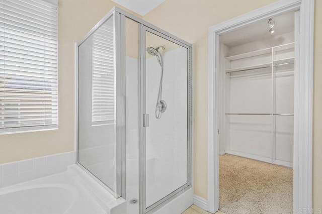 bathroom with a walk in closet, a garden tub, and a stall shower