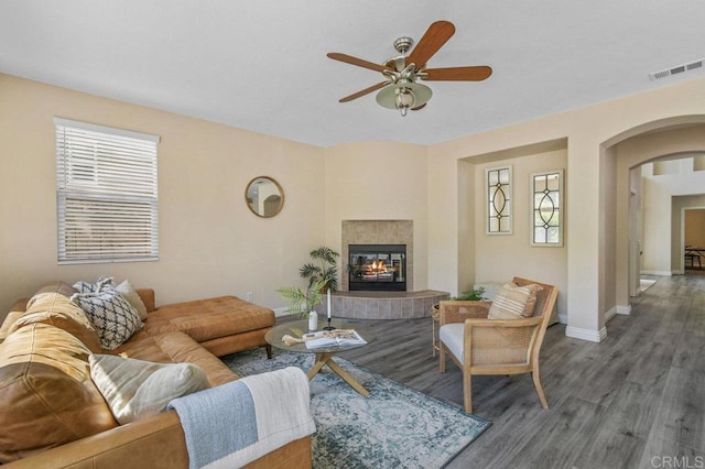living area with visible vents, wood finished floors, a healthy amount of sunlight, ceiling fan, and arched walkways