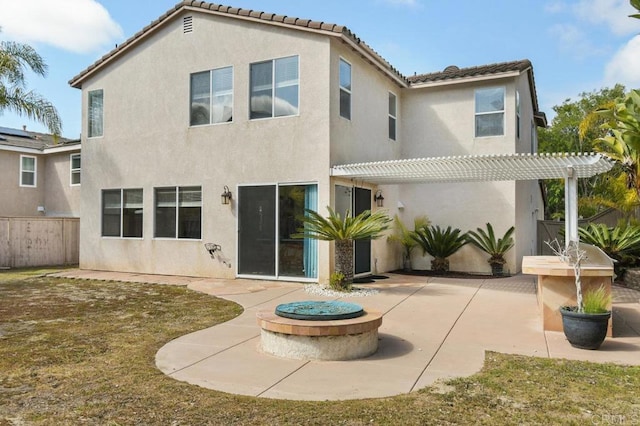 back of house with a tiled roof, a patio area, an outdoor fire pit, a pergola, and stucco siding