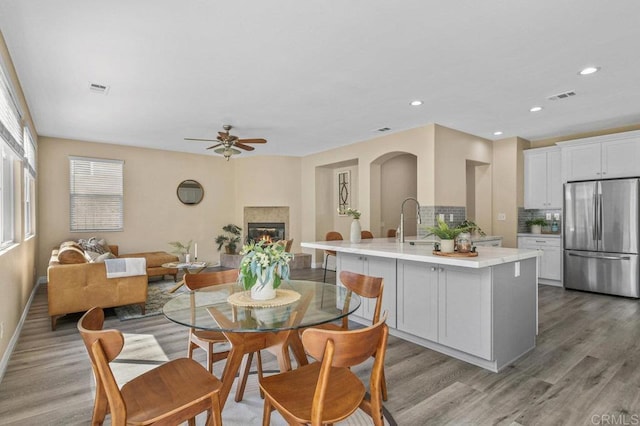 dining room with visible vents, a glass covered fireplace, ceiling fan, and light wood-type flooring