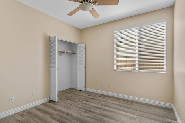 unfurnished bedroom featuring baseboards, ceiling fan, wood finished floors, and a closet