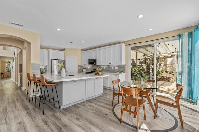 kitchen featuring decorative backsplash, appliances with stainless steel finishes, a healthy amount of sunlight, and arched walkways