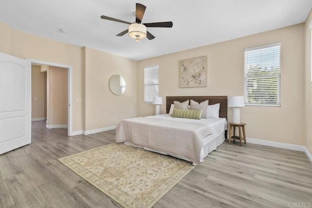 bedroom with a ceiling fan, baseboards, and light wood-style floors