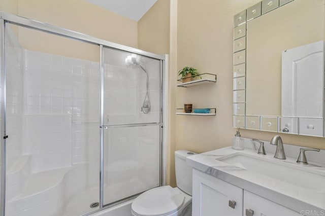 bathroom with toilet, a shower stall, and vanity