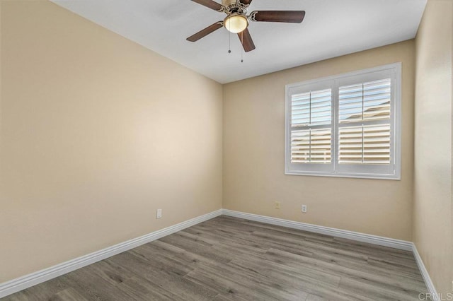 spare room with baseboards, ceiling fan, and wood finished floors