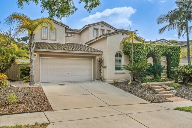 mediterranean / spanish house featuring stucco siding, fence, a tile roof, and concrete driveway