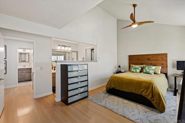 bedroom featuring baseboards, ensuite bathroom, wood finished floors, and lofted ceiling
