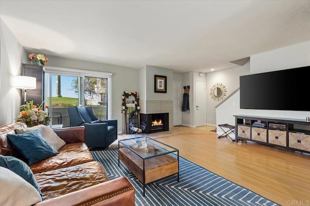 living room with baseboards, wood finished floors, and a lit fireplace