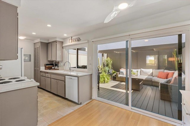 kitchen featuring white appliances, gray cabinetry, a sink, and light countertops