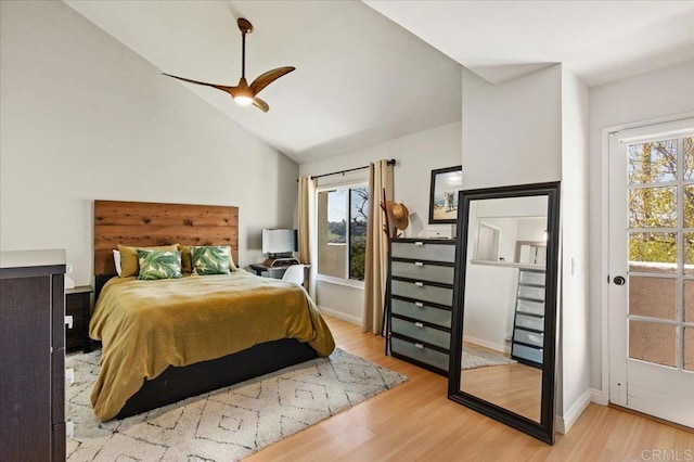 bedroom with baseboards, light wood finished floors, vaulted ceiling, and multiple windows