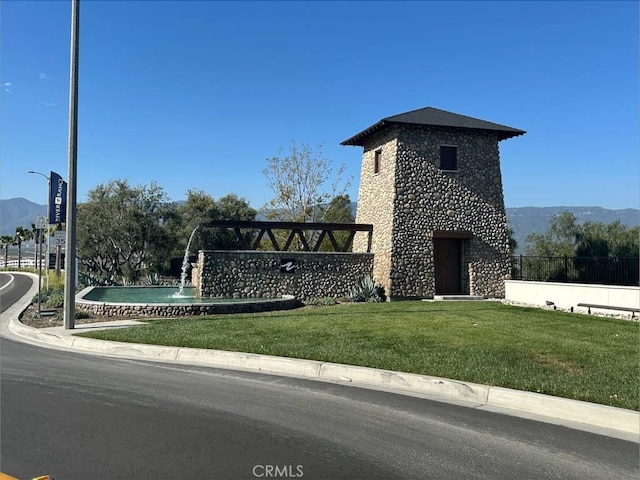 view of side of home with a lawn, a mountain view, and stone siding