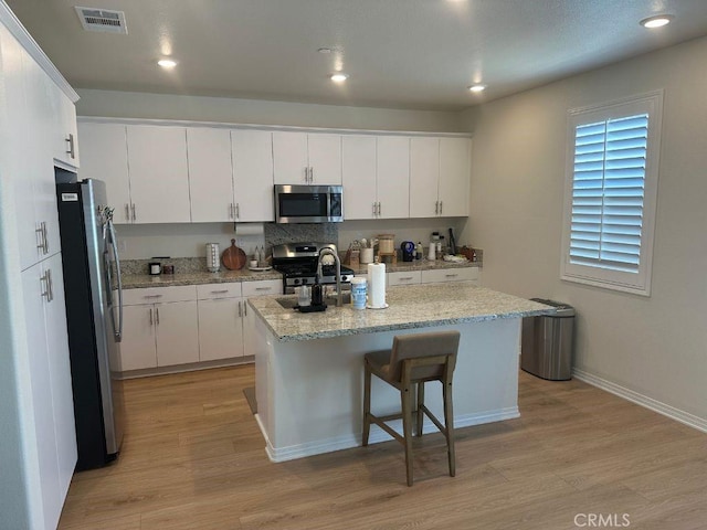 2511 Gunner Ridge Way, Rialto, CA 92377 - kitchen with stainless steel appliances, light wood finished floors, white cabinets, a kitchen island with sink, and recessed lighting