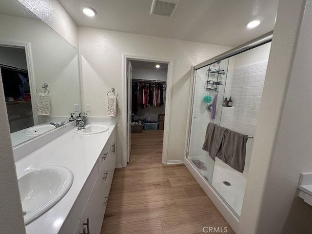 2511 Gunner Ridge Way, Rialto, CA 92377 - bathroom featuring a shower stall, double vanity, a walk in closet, wood finished floors, and recessed lighting