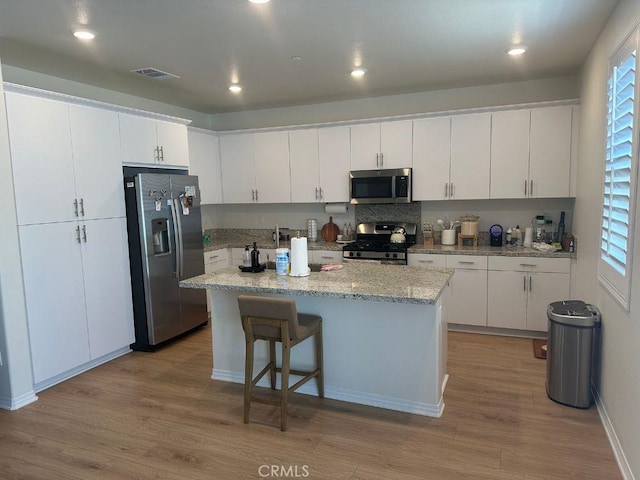 2511 Gunner Ridge Way, Rialto, CA 92377 - kitchen with stainless steel appliances, light wood-type flooring, white cabinetry, a center island, and recessed lighting