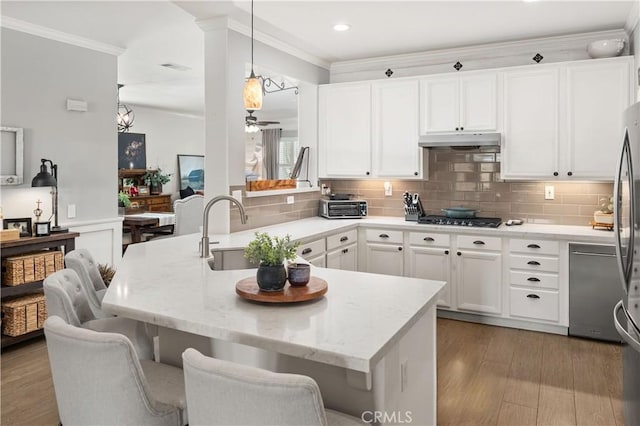 27975 Langley Pl, Castaic, CA 91384 - kitchen featuring under cabinet range hood, gas cooktop, crown molding, light stone countertops, and tasteful backsplash