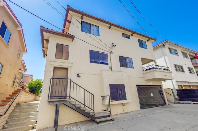 814 S Patton Ave Unit 2, San Pedro, CA 90731 - rear view of property featuring stairs, stucco siding, a garage, and a balcony