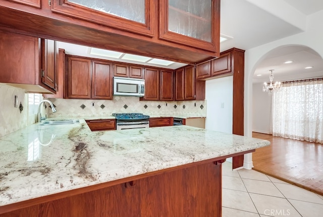 814 S Patton Ave Unit 2, San Pedro, CA 90731 - kitchen featuring range with gas stovetop, stainless steel microwave, a sink, a chandelier, and light stone counters