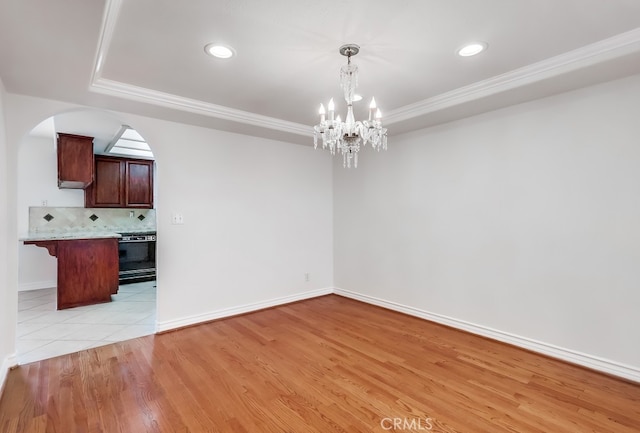 814 S Patton Ave Unit 2, San Pedro, CA 90731 - unfurnished dining area featuring a tray ceiling, a chandelier, arched walkways, crown molding, and light wood finished floors
