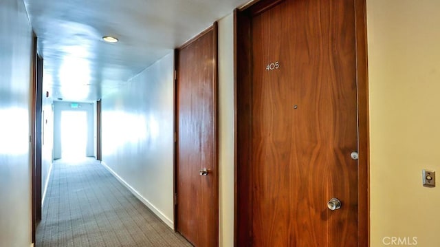 corridor featuring baseboards and carpet