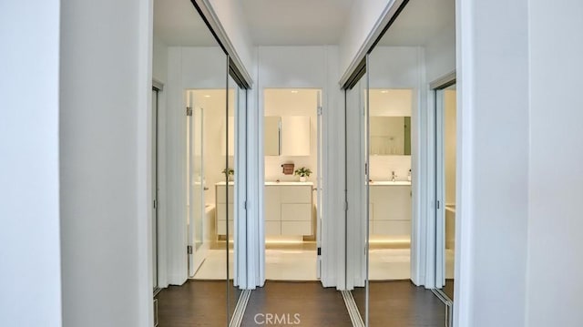 corridor with dark wood finished floors and a sink