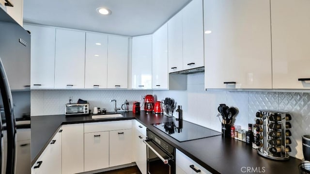 kitchen with dark countertops, a sink, a toaster, tasteful backsplash, and black appliances