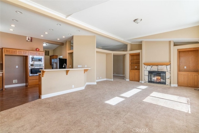 unfurnished living room featuring a stone fireplace, vaulted ceiling, baseboards, light carpet, and recessed lighting
