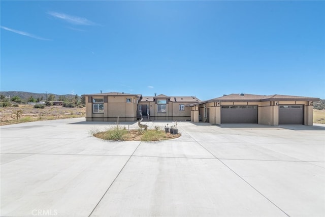 view of front of property featuring a garage, a mountain view, stucco siding, and concrete driveway