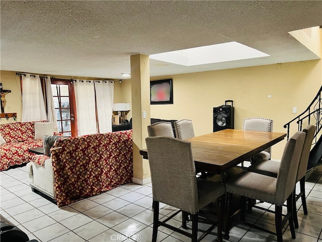 dining area with a textured ceiling, light tile patterned flooring, and a skylight