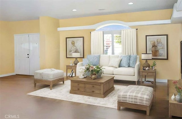 living area featuring baseboards, recessed lighting, wood finished floors, and an AC wall unit