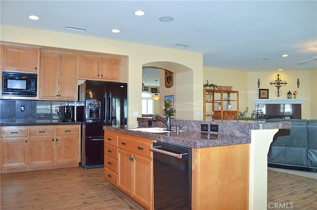 kitchen featuring a sink, arched walkways, open floor plan, light wood-type flooring, and black appliances