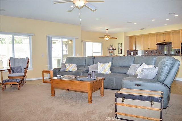 living area with light colored carpet, ceiling fan, and a wealth of natural light