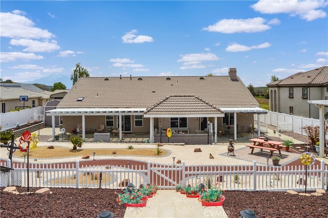 back of property with a patio, a fenced backyard, a tiled roof, and a gate