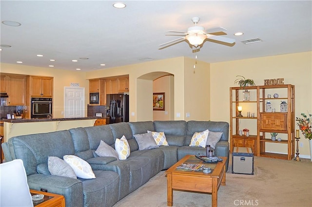 living area with visible vents, ceiling fan, recessed lighting, light colored carpet, and arched walkways