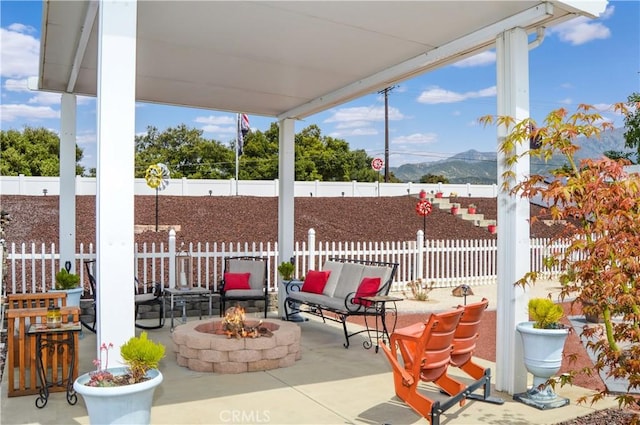view of patio featuring a mountain view, fence private yard, and an outdoor fire pit