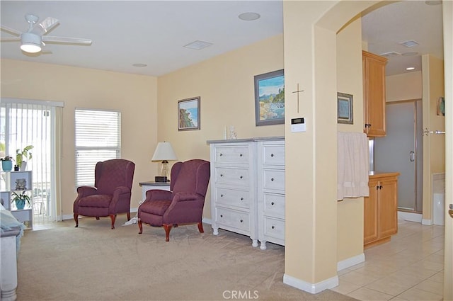 living area with baseboards, arched walkways, a ceiling fan, and light colored carpet