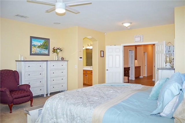 bedroom featuring arched walkways, ensuite bathroom, a ceiling fan, and visible vents