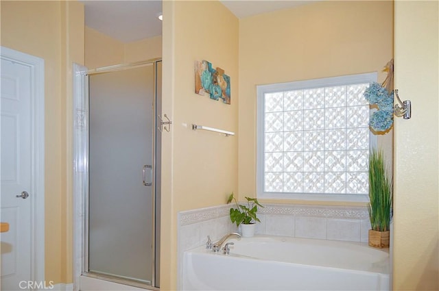 full bathroom featuring a shower stall, a garden tub, and plenty of natural light